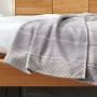 Couverture douillette avec motif dynamique composé de lignes filigranes, losange et pois dans des nuances de gris élégantes