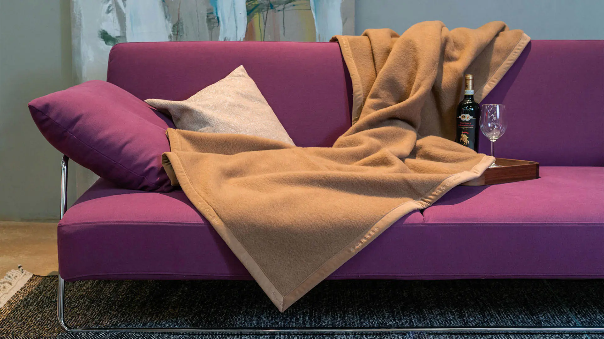 Couverture en laine de poil de bébé chameau en coloris chameau, étendue sur un canapé