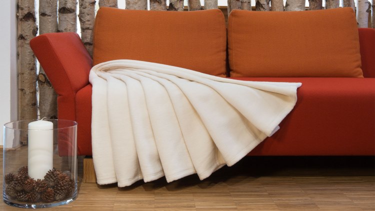 Couverture polaire dans un coloris naturel clair sur un sofa
