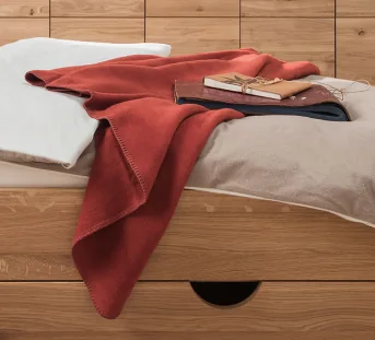 Gezellige katoenen pluche deken op bed - hier in het rood